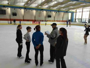 Foto von TeilnehmerInnen mit Trainer auf der Eisfläche stehend
