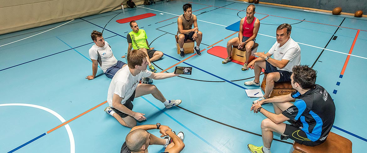 Headerbild der BSPA Wien - Sportgruppe mit Trainer sitzt im Turnsaal