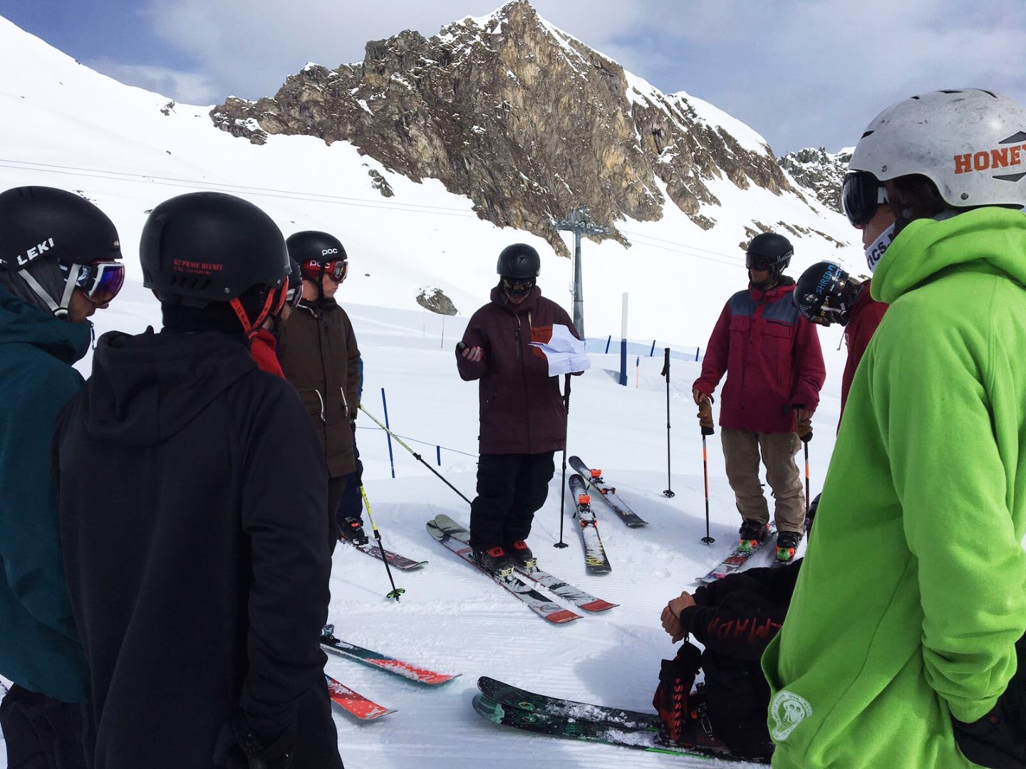 ein Lehrer der Ski Freestyle / Freeski Instruktorenausbildung unterrichtet auf der Piste, die TeilnehmerInnen hören zu.
