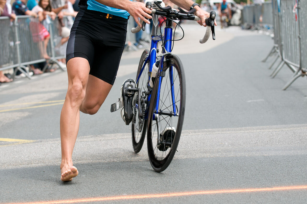 Eine Person beim barfuß beim Fahrrad schieben in der Wechselzone.