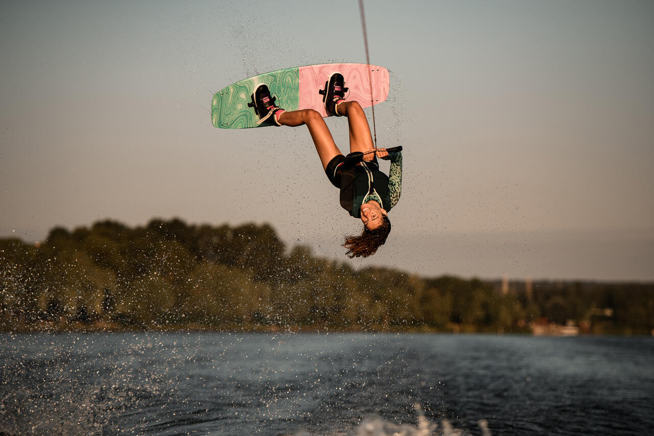 Eine Person am Wakeboard in der Luft Kopf über Wasser.