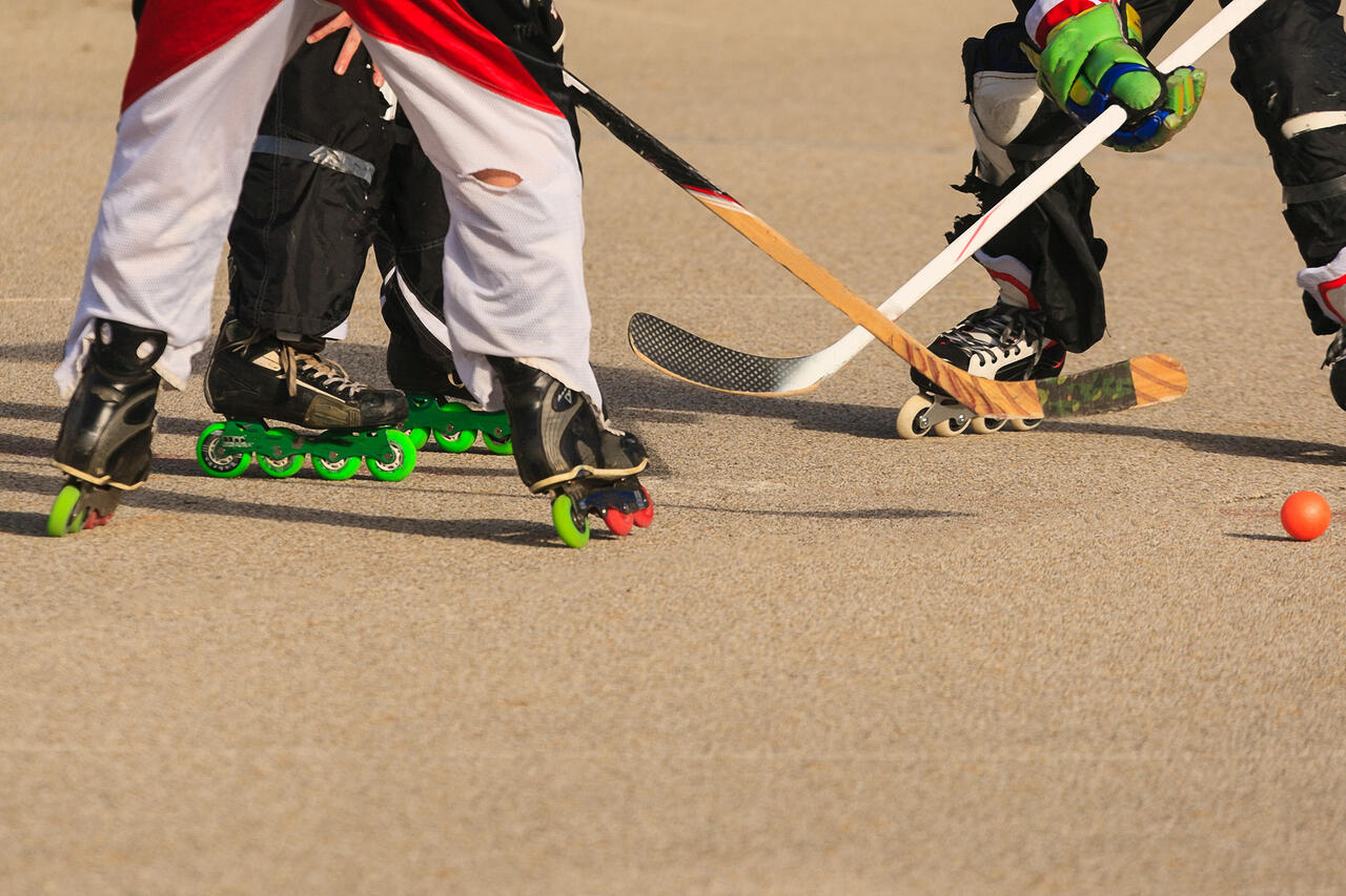 Sechs Beine mit Skates, Schläger und Ball.