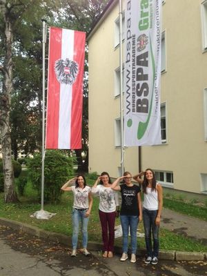 Foto der neuen Flagge der BSPA Graz und den darunter stehenden Mitarbeiterinnen