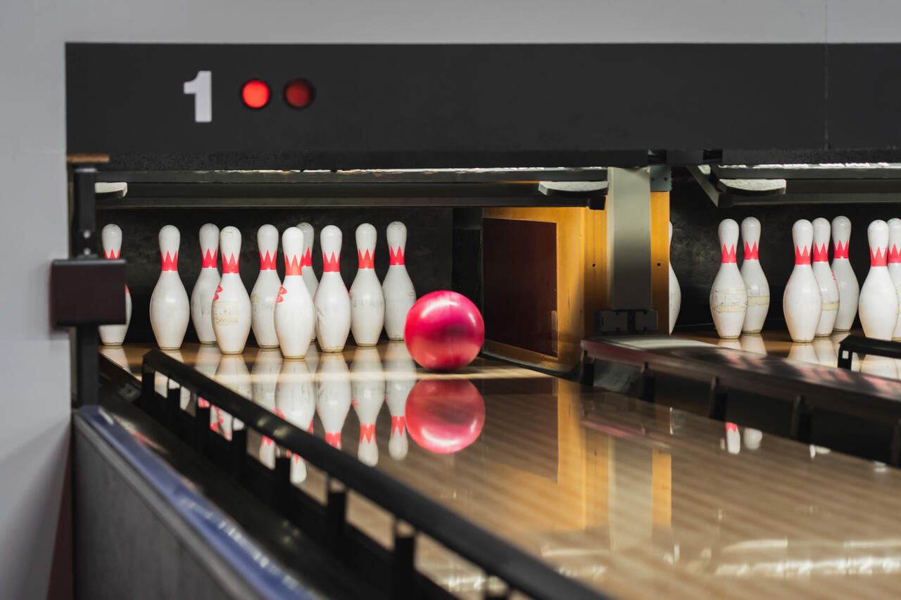 Bild zeigt viele Kegeln, eine Kugel und die Bowling-Bahn.