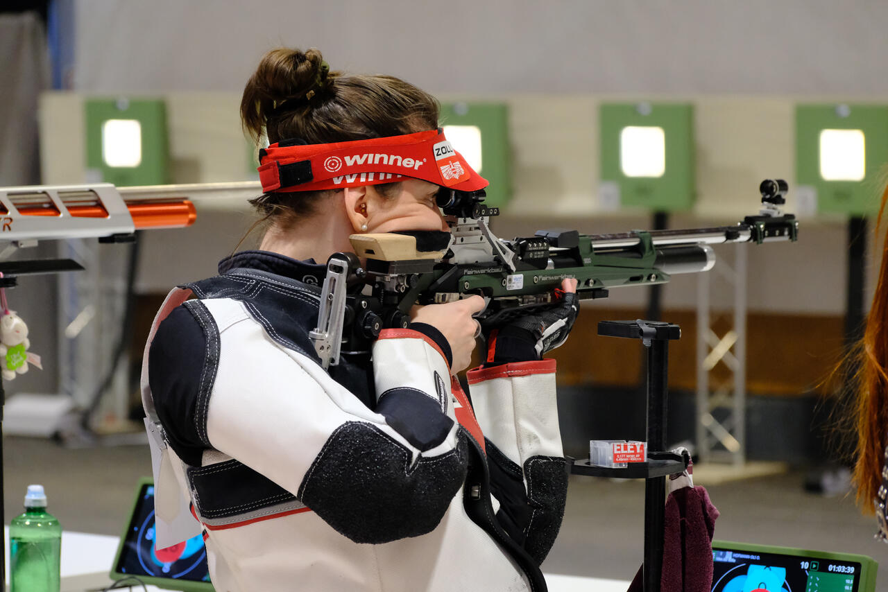 Eine Person mit Gewehr in der Hand beim Zielen.