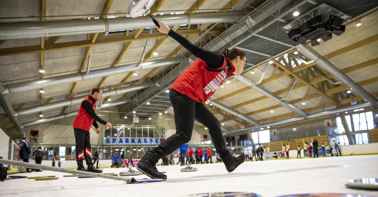 Eisstocksportlerin kurz vor dem Abstoß des Stockes.